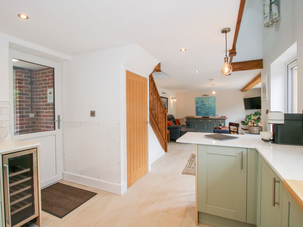 A kitchen with a wine fridge and stairs at Sylva Cottage in Burlton near Cockshutt