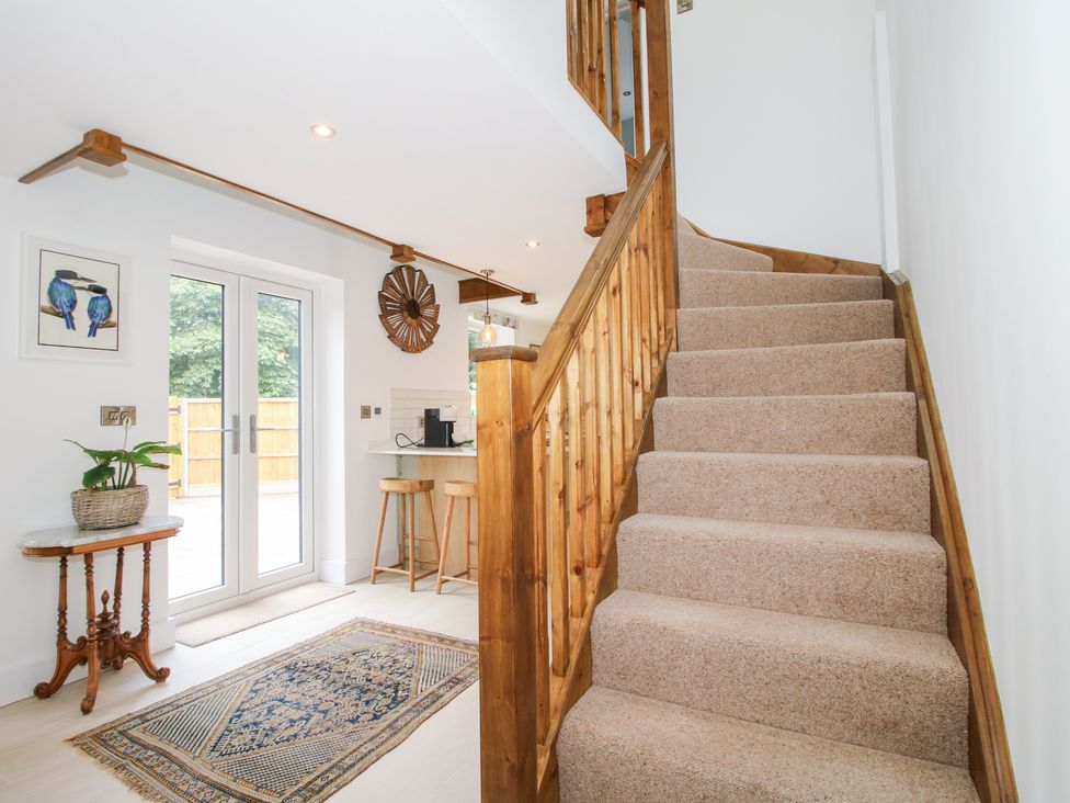 A staircase with wooden railing and door leading to the outdoor patio at Sylva Cottage Burlton near Cockshutt