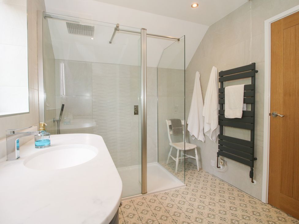 A bathroom with a shower, sink, and towels at Sylva Cottage in Burlton near Cockshutt