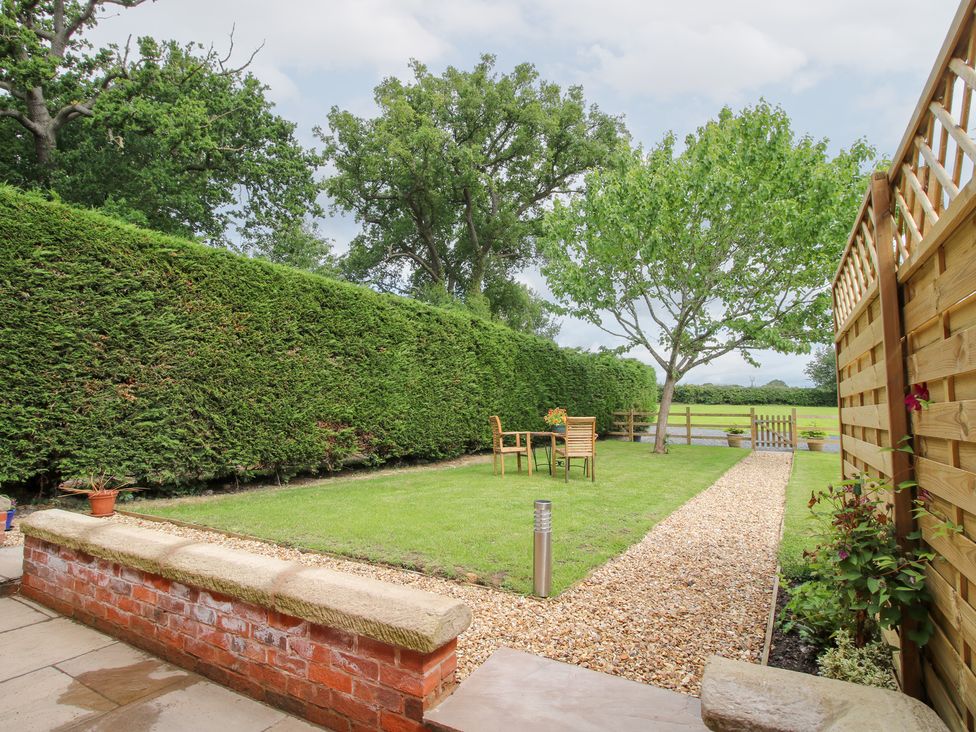 A garden with a table and chairs surrounded by hedges at Sylva Cottage in Burlton near Cockshutt