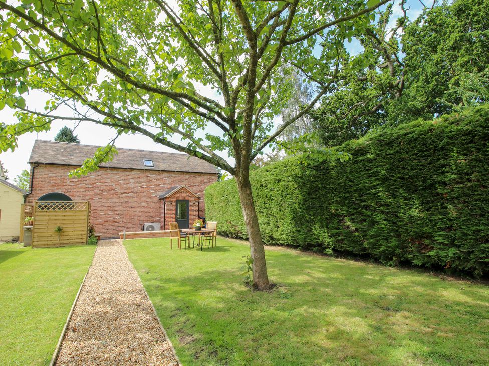 A garden with a tree and outdoor furniture at Sylva Cottage in Burlton near Cockshutt