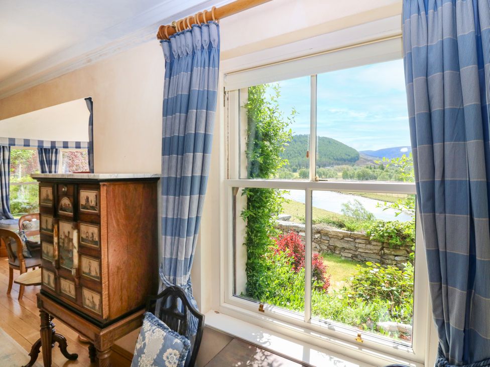 A living room with a window and cabinet at Claybockie near Mar Lodge Braemar