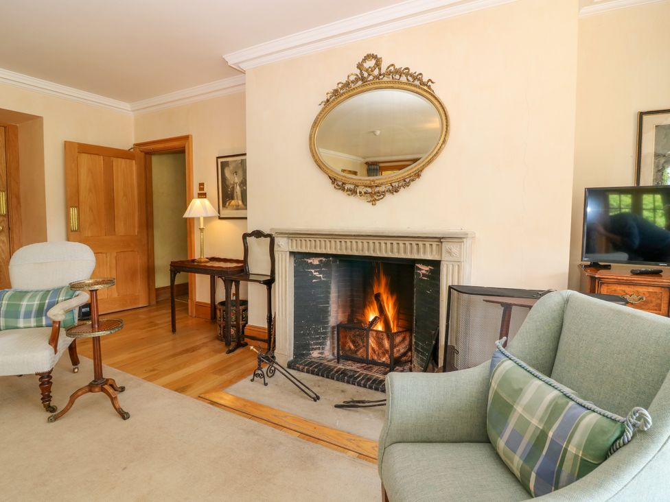A living room with a fireplace and a chair at Claybockie near Braemar