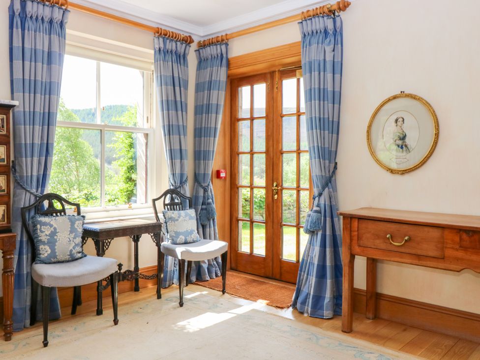A sitting room with blue curtains and a wooden table at Claybockie, Mar Lodge near Braemar