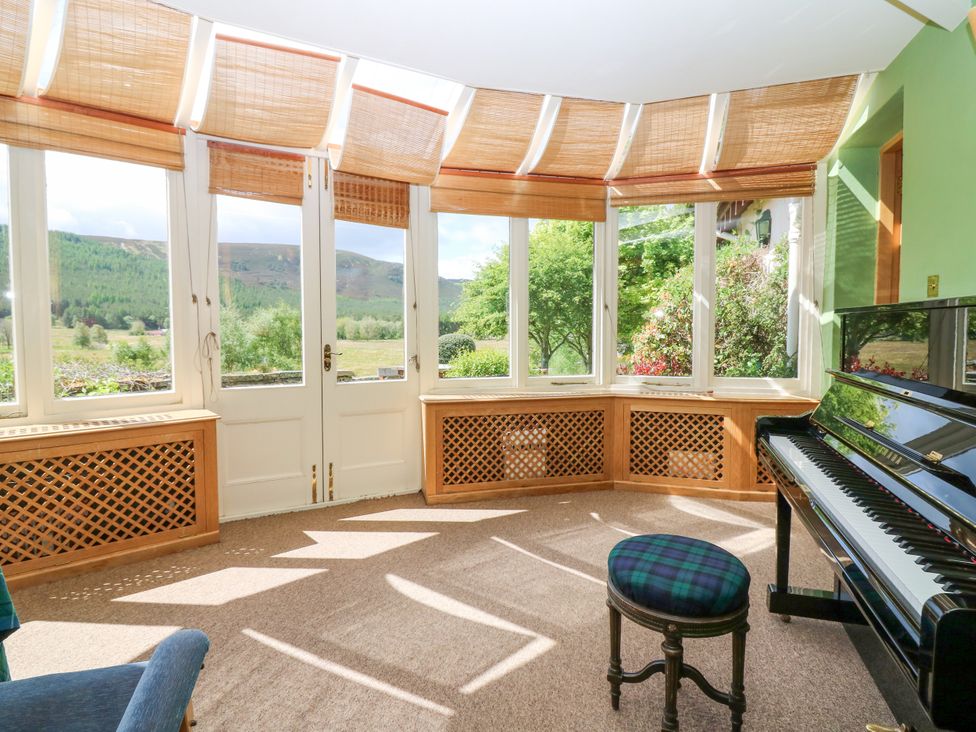 A sunroom with a piano and windows at Claybockie near Braemar