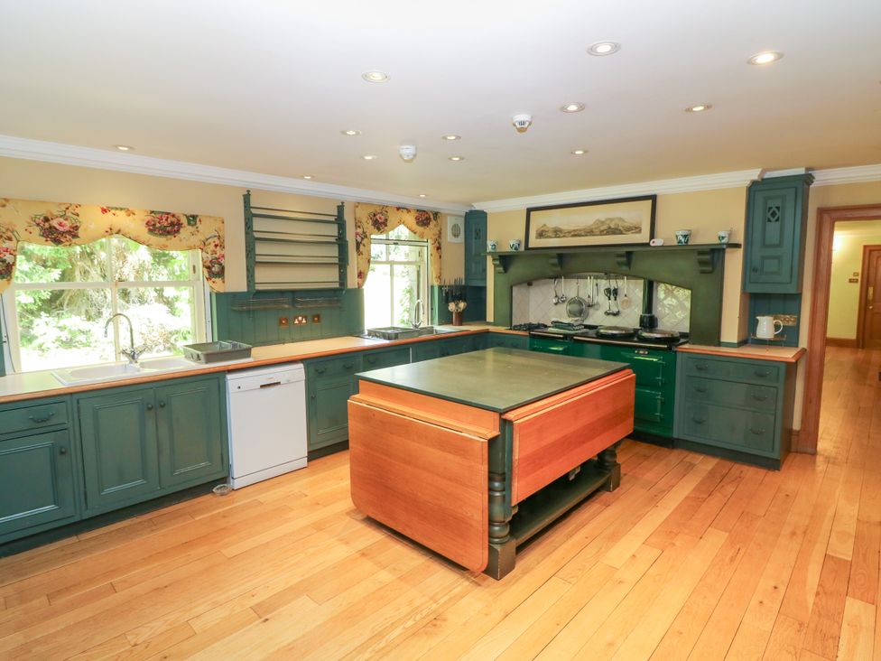 A kitchen with green cabinets and an island at Claybockie near Braemar