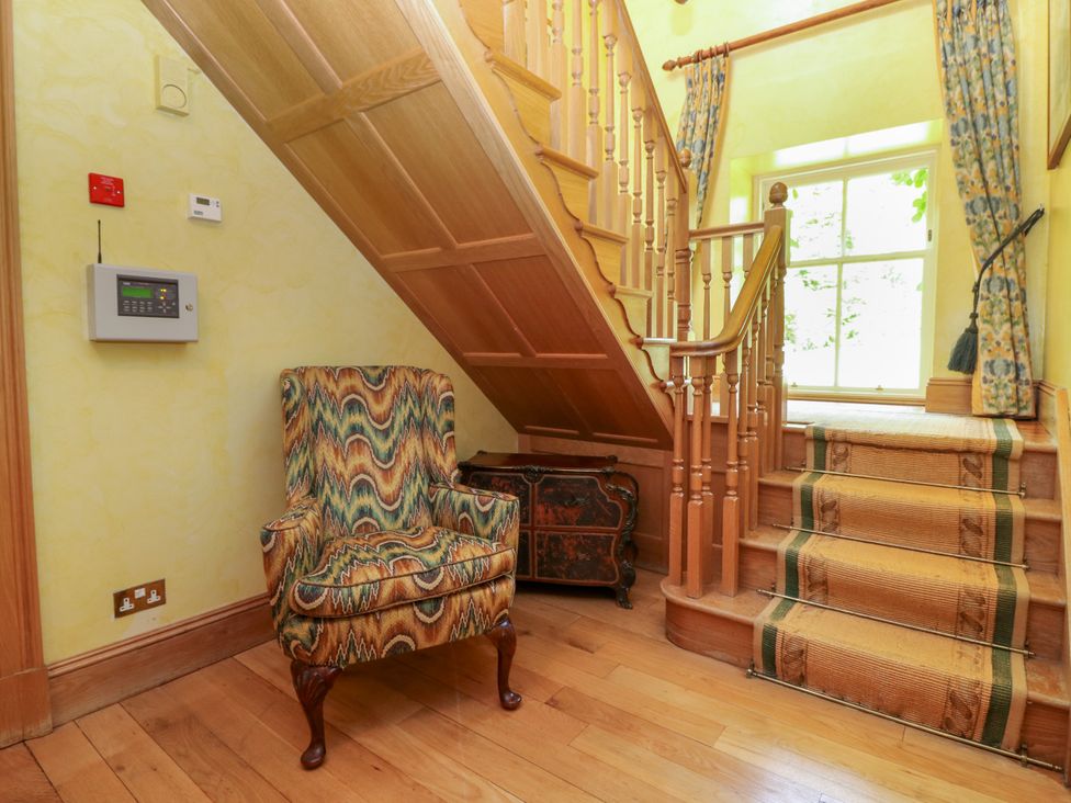 A hallway with a chair and stairs at Claybockie near Mar Lodge near Braemar
