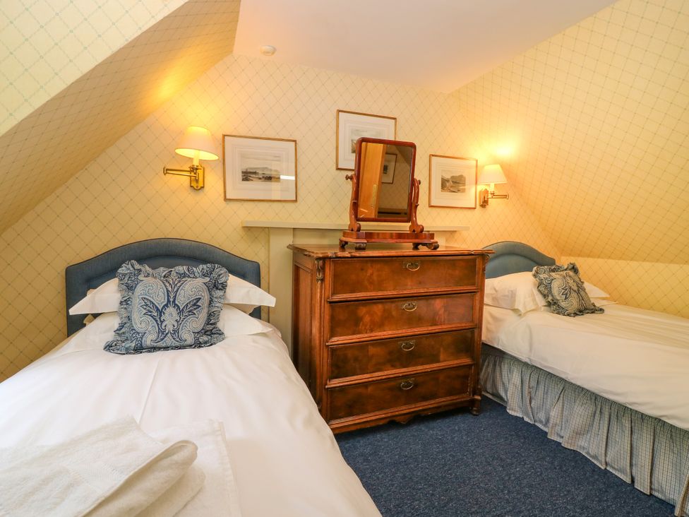 A bedroom with two beds and a wooden dresser with a mirror at Claybockie Mar Lodge near Braemar