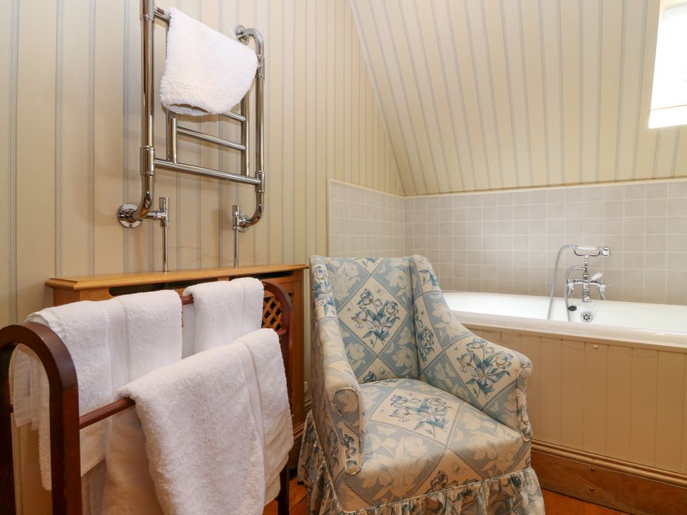 A bathroom with a bathtub and a chair at Claybockie near Braemar