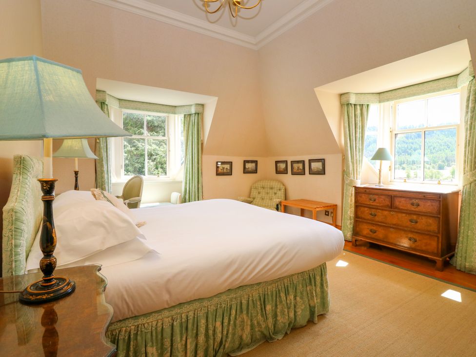 A bedroom with a bed, lamp, chair, and chest of drawers at Claybockie in Mar Lodge near Braemar