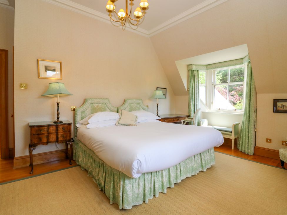 A bedroom with a bed, nightstand, lamp, and window at Claybockie Mar Lodge near Braemar