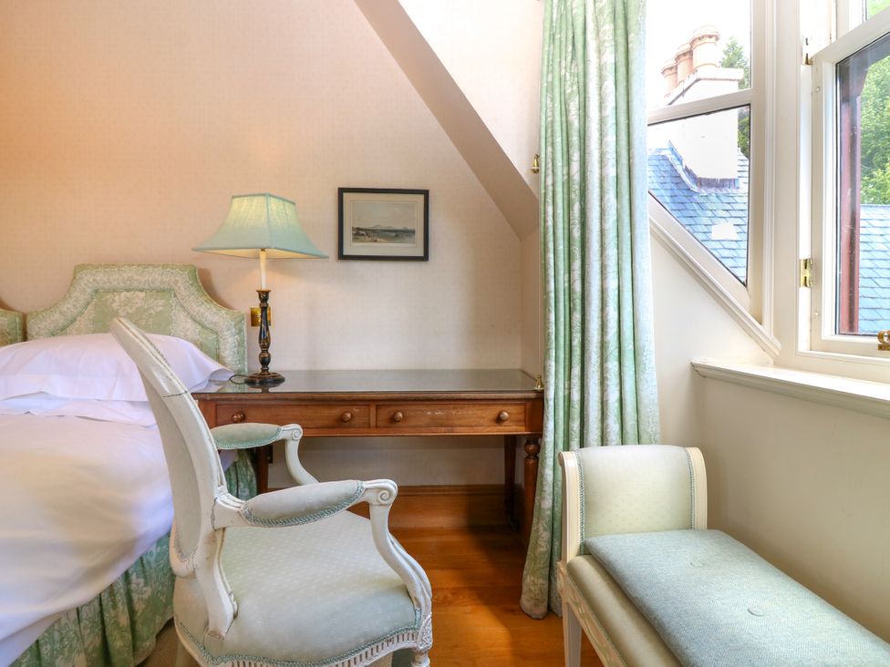 A bedroom with a bed, chair, desk, and lamp at Claybockie, Mar Lodge near Braemar