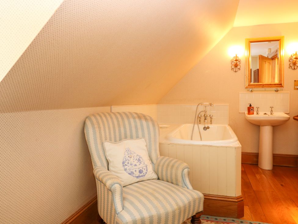 A bathroom with a bathtub, sink, and chair at Claybockie Mar Lodge near Braemar