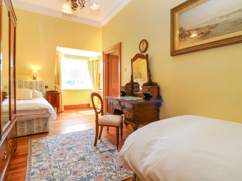 A bedroom with a bed, mirror, and chair at Claybockie near Braemar