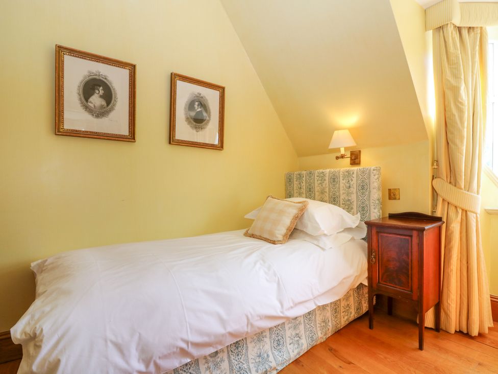 A bedroom with a single bed and framed pictures at Claybockie near Mar Lodge