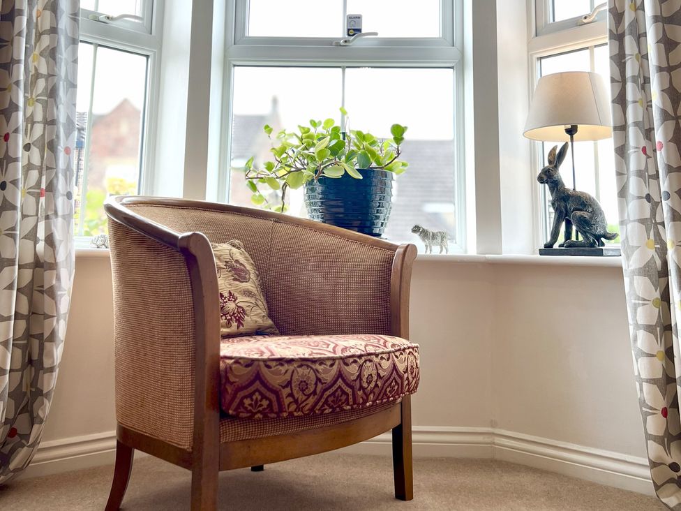 A living room with a chair and a plant on a windowsill at Harefield in Rothbury