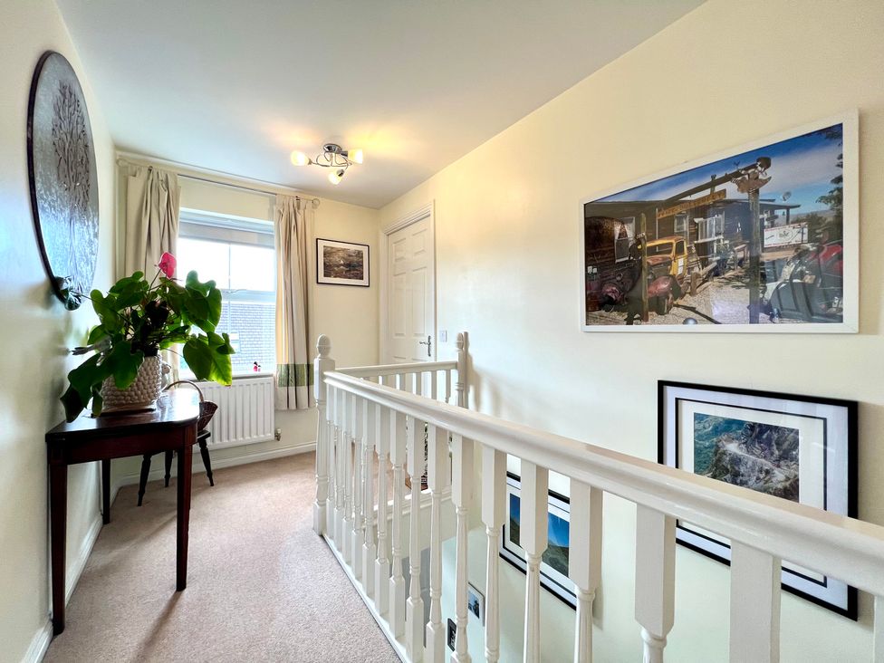 A hallway with a plant on a table and photographs on the wall at Harefield in Rothbury