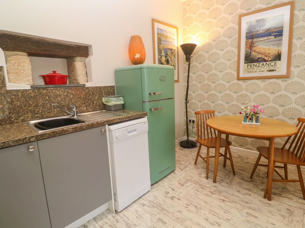 A kitchen with appliances and dining table at The Stable in Rosudgeon