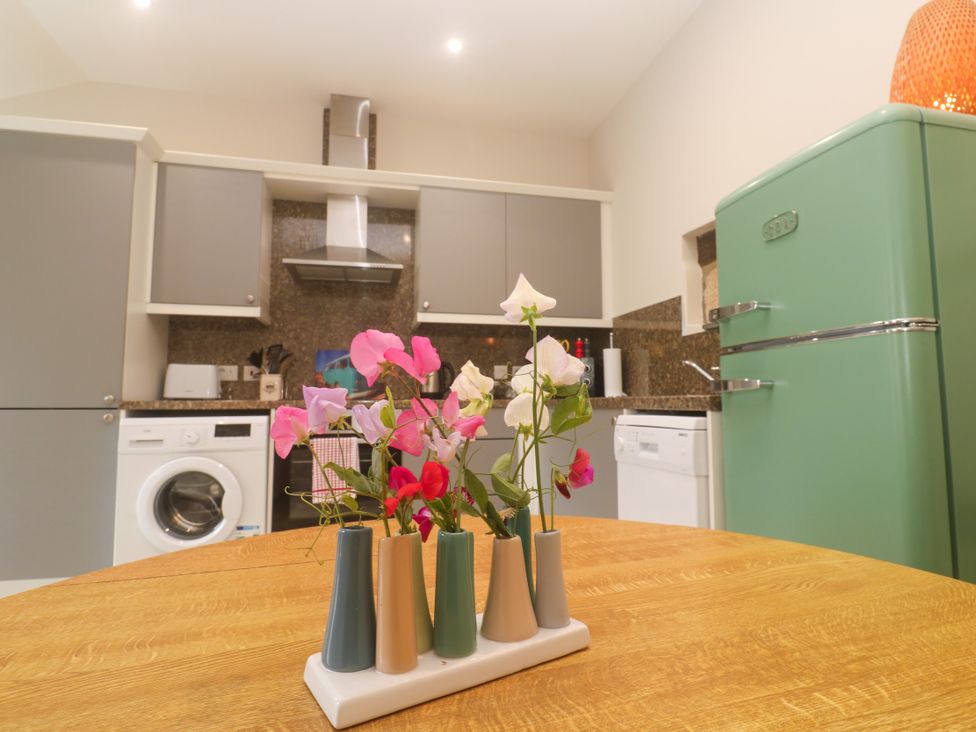 A kitchen with a table and flowers at The Stable in Rosudgeon