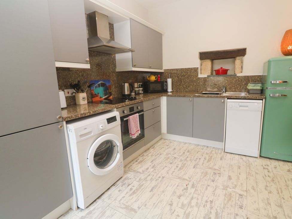 A kitchen with appliances including a washing machine and refrigerator at The Stable in Rosudgeon
