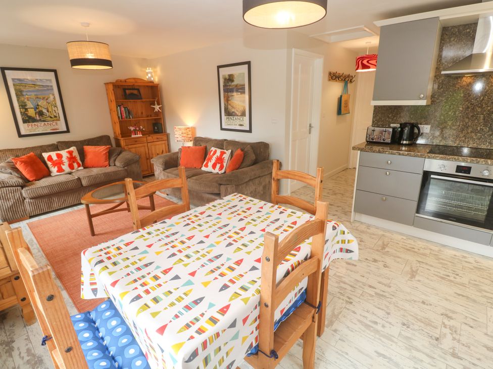 A living room with a sofa and a kitchen unit at Sea View Loft in Rosudgeon