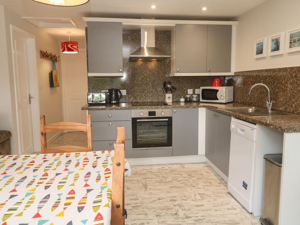 A kitchen with appliances and a dining table at Sea View Loft in Rosudgeon