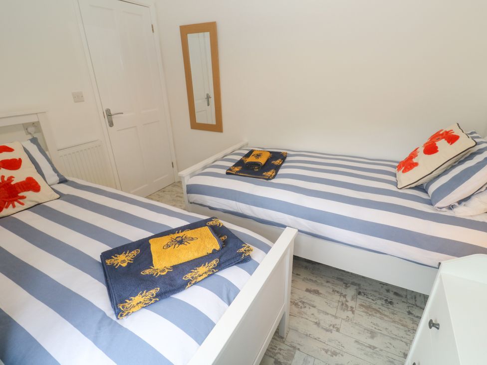 A bedroom with two single beds and a mirror at Sea View Loft in Rosudgeon