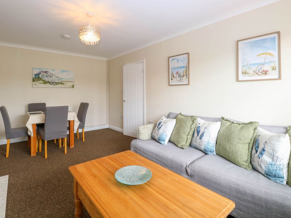A living room with a gray sofa with cushions and a wooden coffee table with a decorative bowl at Little Lodge in Dersingham