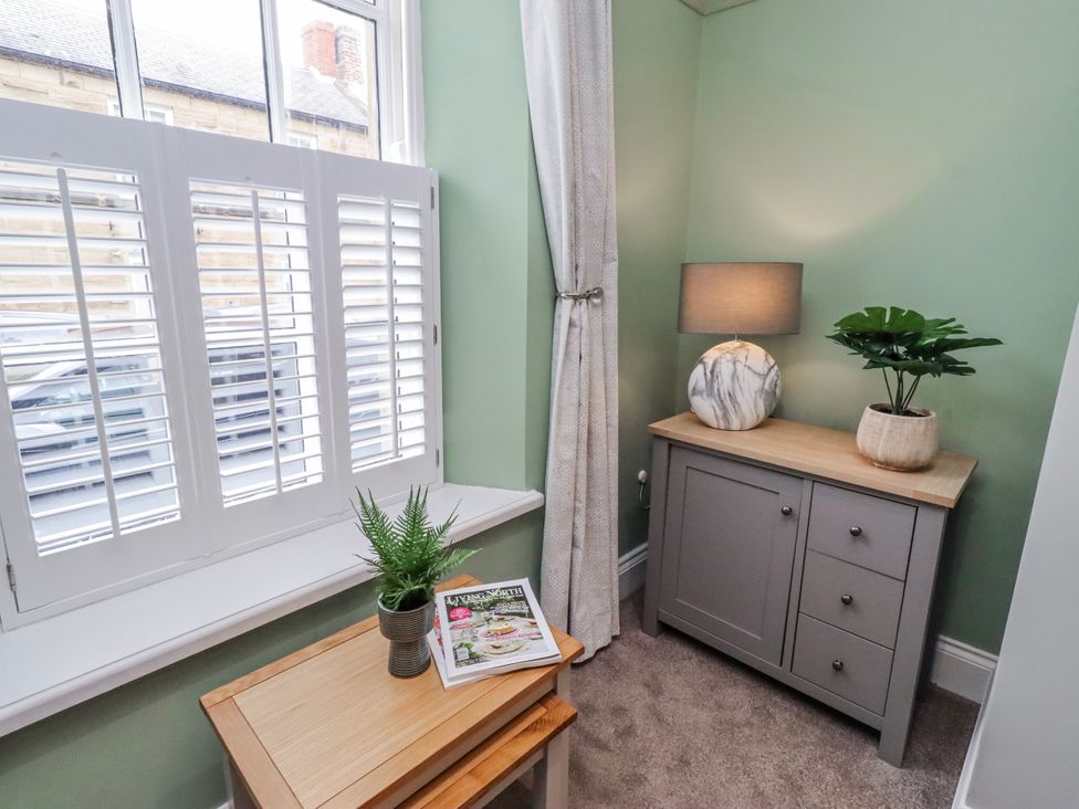 A corner with a cabinet, lamp, plant, and magazine at 3 Lisburn Street Alnwick