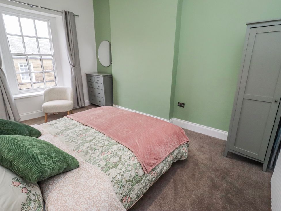 A bedroom with a bed and a chair at 3 Lisburn Street Alnwick