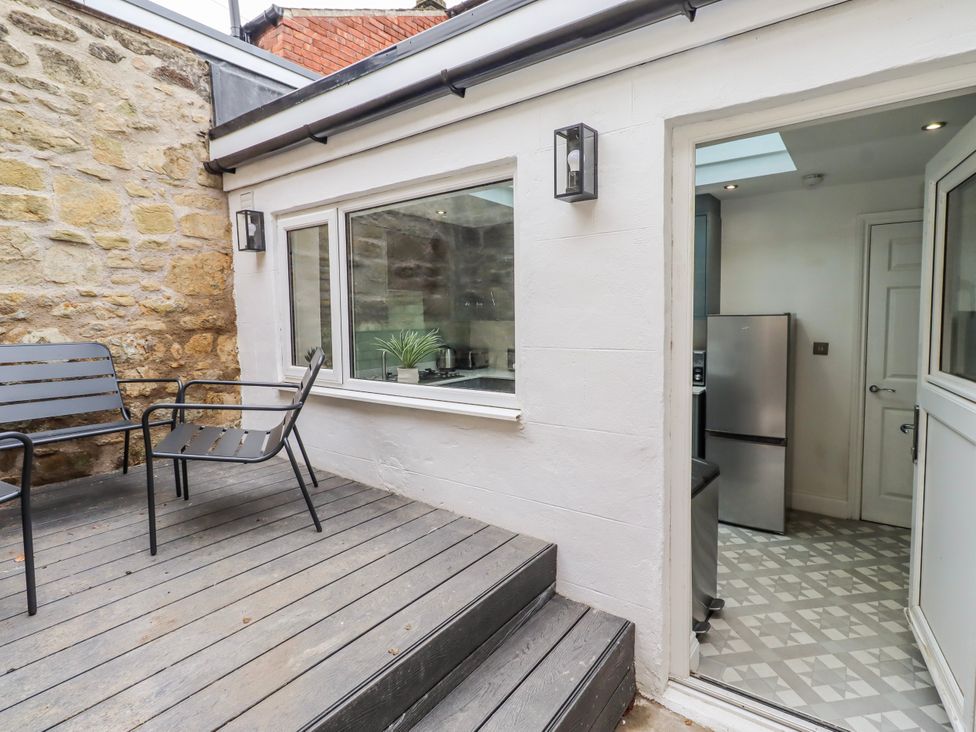 An outdoor seating area with chairs and a door leading to a kitchen at 3 Lisburn Street Alnwick