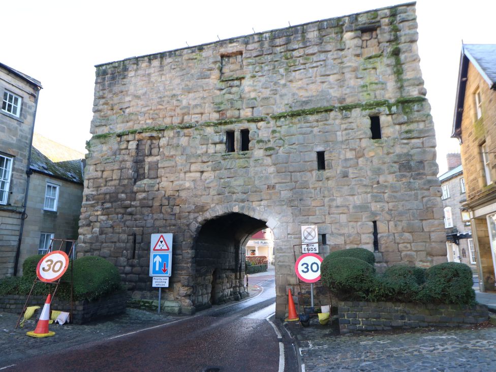 A stone archway with road signs and bushes at Middle Cottage in Alnwick