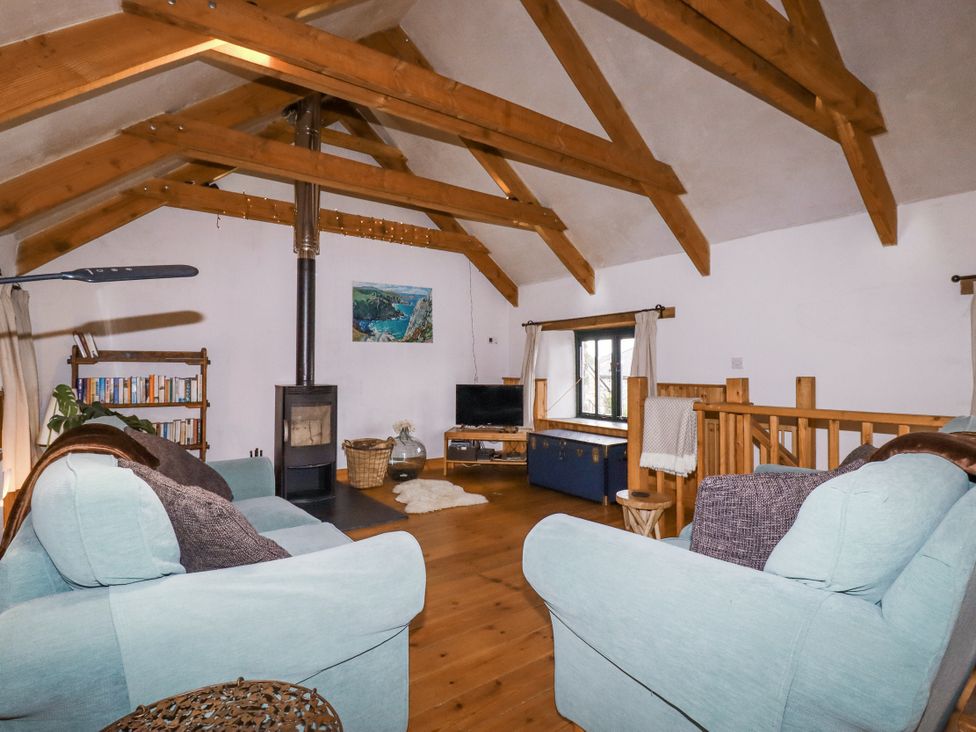 A living room with a sofa and wood stove at Coombe Barn Cusgarne near St Day