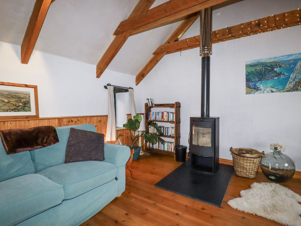 A living room with a wood stove and bookshelves at Coombe Barn in Cusgarne near St Day