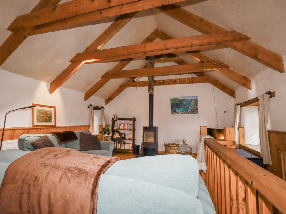 A living room with a fireplace and bookshelf at Coombe Barn in Cusgarne near St Day