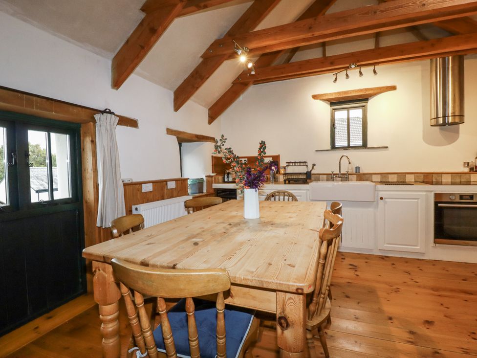 A kitchen with a dining table and wooden chairs at Coombe Barn Cusgarne near St Day