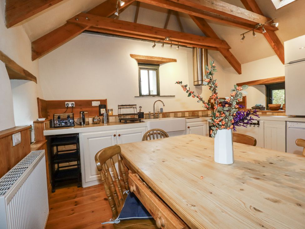 A kitchen with a wooden table and chairs at Coombe Barn Cusgarne near St Day
