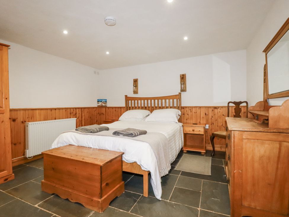 A bedroom with a bed and wooden furniture at Coombe Barn in Cusgarne near St Day