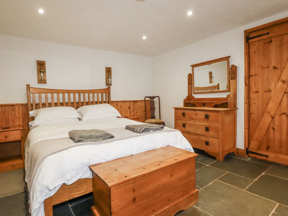 A bedroom with a bed, dresser and mirror at Coombe Barn in Cusgarne near St Day