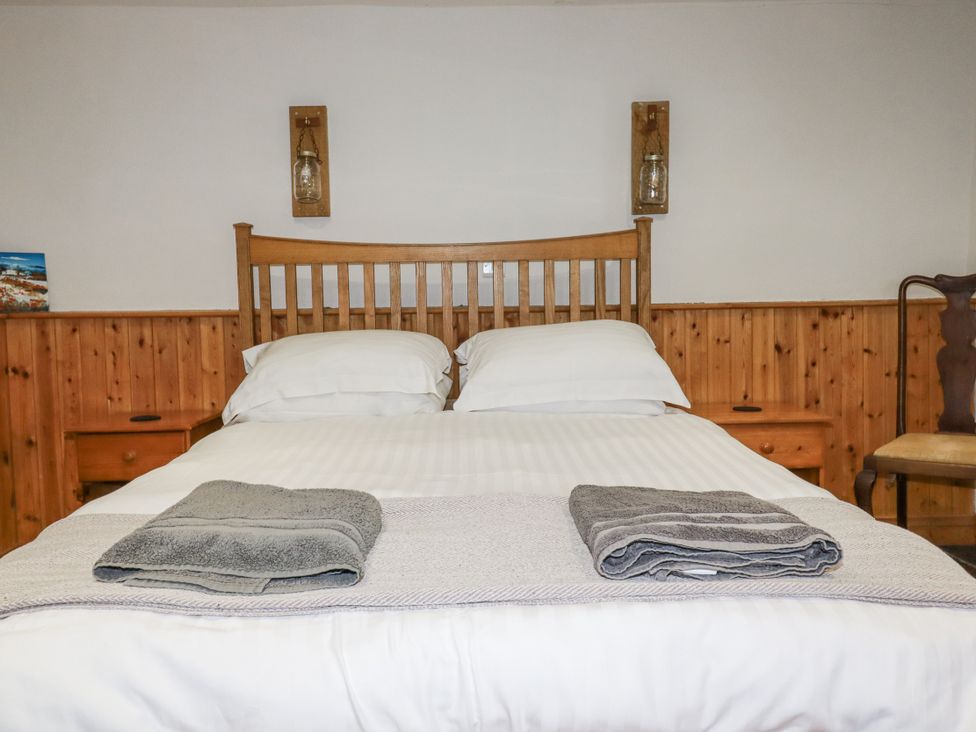 A bedroom with a wooden bed and towels at Coombe Barn Cusgarne near St Day