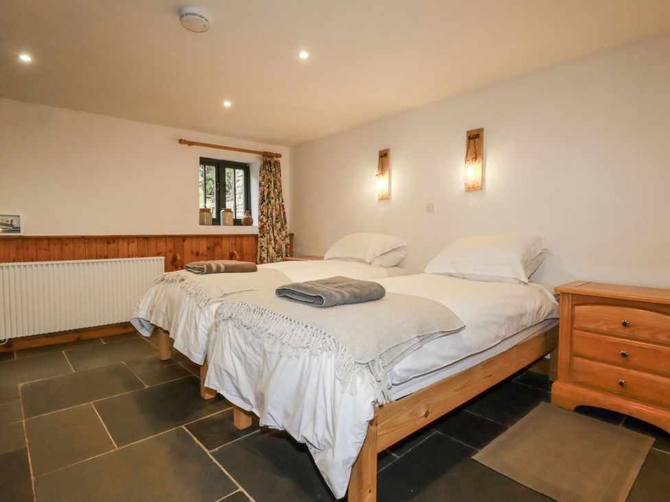 A bedroom with two beds and a window at Coombe Barn Cusgarne near St Day