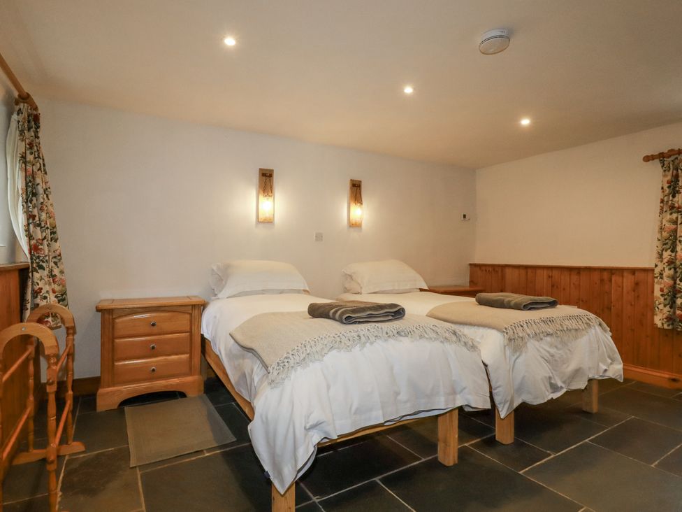 A bedroom with two beds and bedside tables at Coombe Barn Cusgarne near St Day