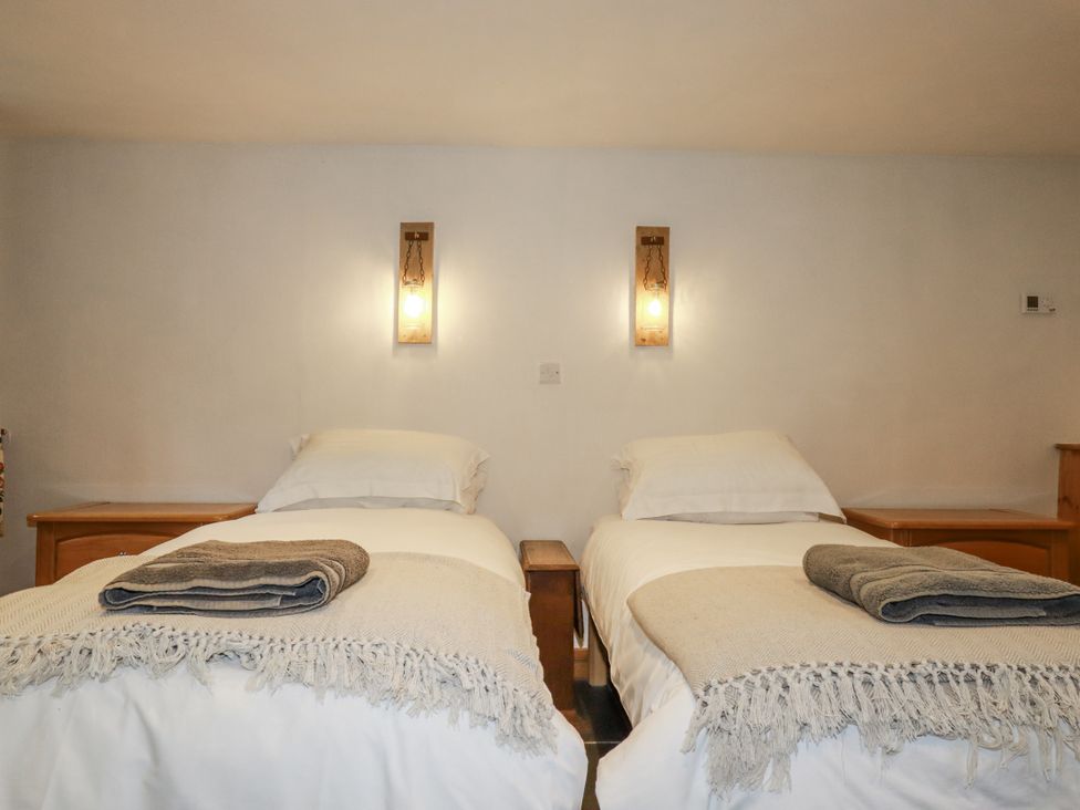 A bedroom with two beds and bedside tables at Coombe Barn in Cusgarne near St Day