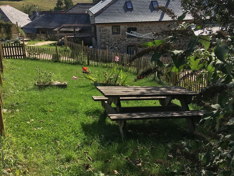 A garden with a picnic table and flowers at Coombe Barn in Cusgarne