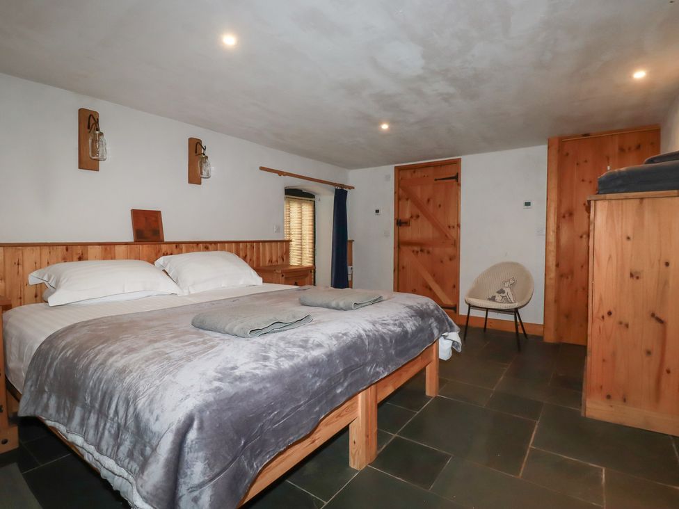 A bedroom with a bed and wooden details at Stribleys Barn in Cusgarne near St Day