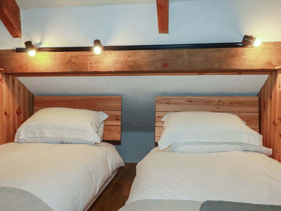 A bedroom with two single beds and wooden headboards at Stribleys Barn Cusgarne near St Day