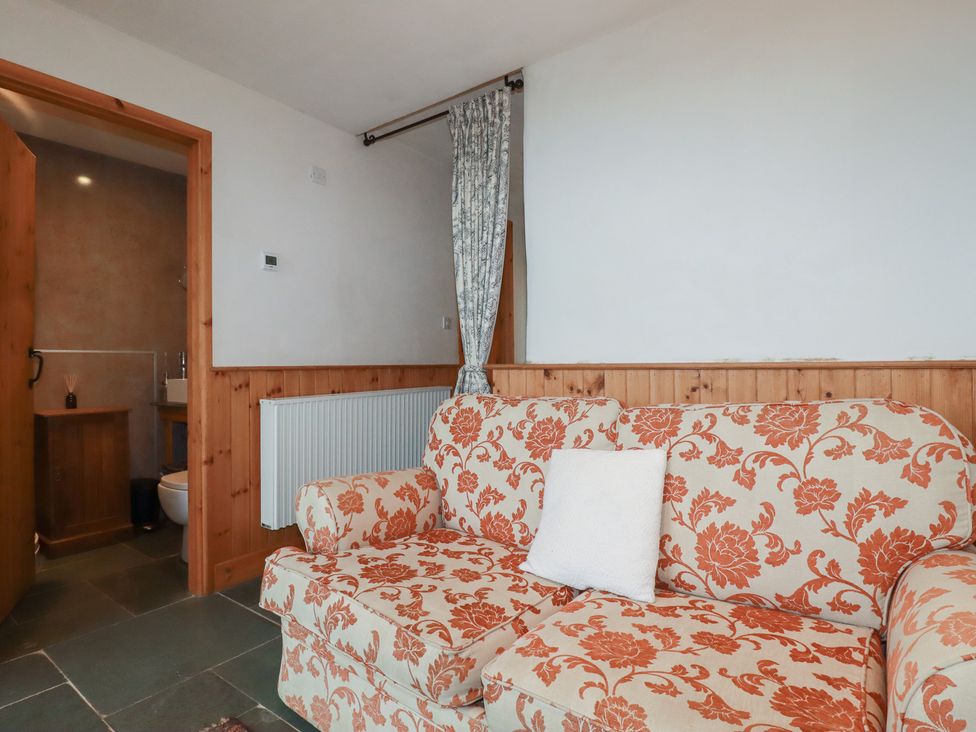 A living room with a sofa and a door leading to the bathroom at Stribleys Barn in Cusgarne near St Day