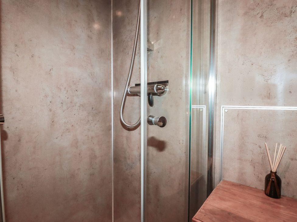 A shower area with a glass panel and wooden surface at Stribleys Barn in Cusgarne near St Day