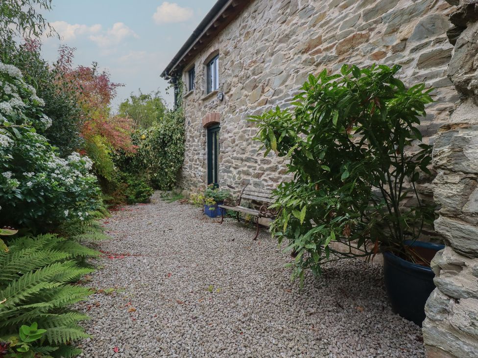 A garden with a stone wall and gravel pathway at Stribleys Barn Cusgarne near St Day