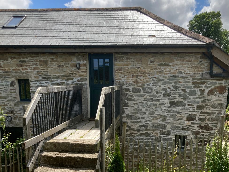 An exterior view of a stone building with a door and steps at Stribleys Barn in Cusgarne